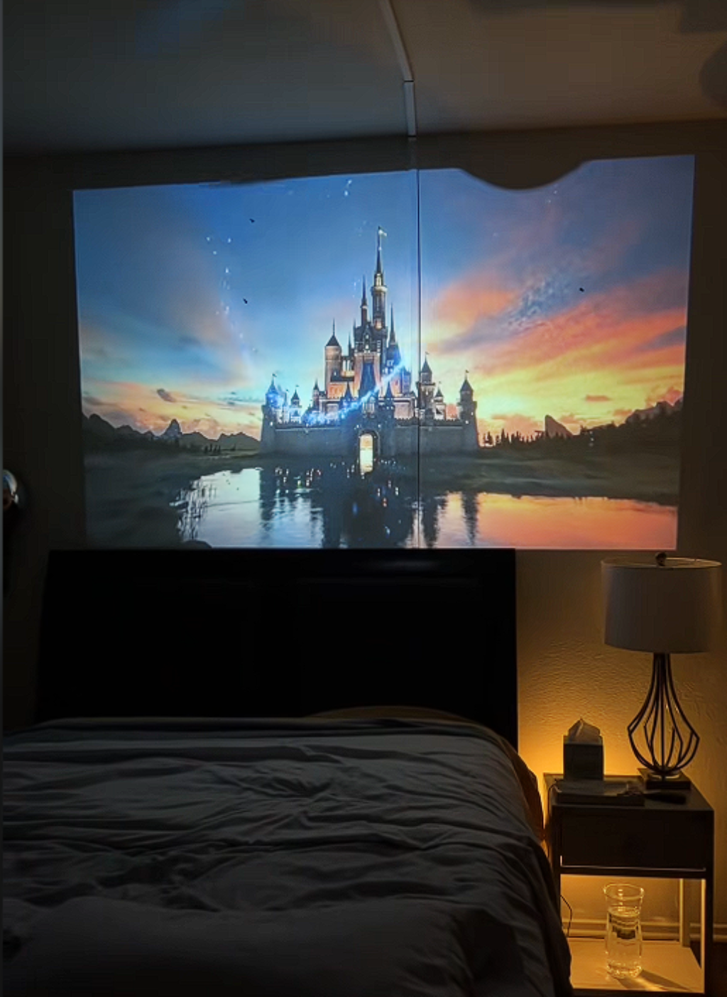 Bedroom with a large screen displaying a castle at sunset.